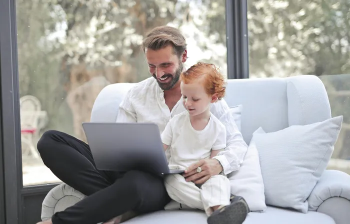 A father and child at home using a laptop together